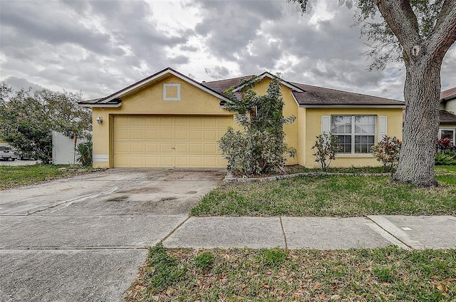 ranch-style home featuring an attached garage, a front yard, concrete driveway, and stucco siding