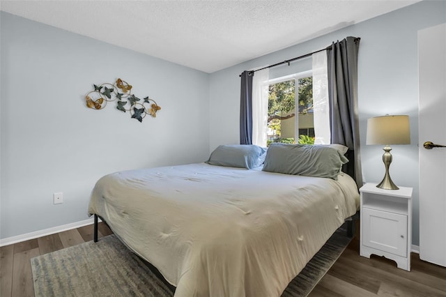 bedroom featuring a textured ceiling, baseboards, and wood finished floors