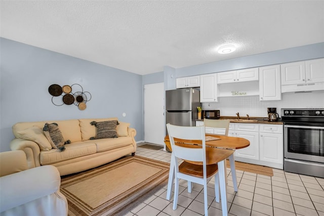 kitchen featuring under cabinet range hood, light tile patterned floors, stainless steel appliances, and a sink