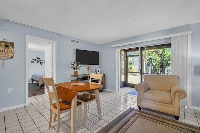 dining room featuring light tile patterned floors, baseboards, visible vents, and a textured ceiling