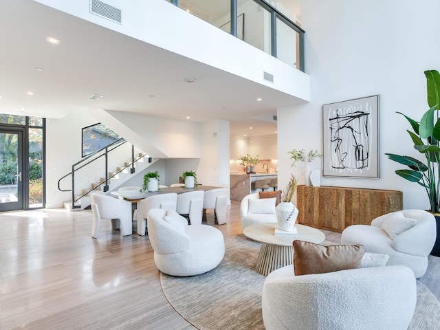 living area featuring a towering ceiling, stairway, wood finished floors, and visible vents