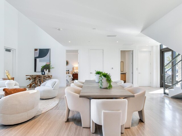 dining area with a towering ceiling, stairs, and recessed lighting