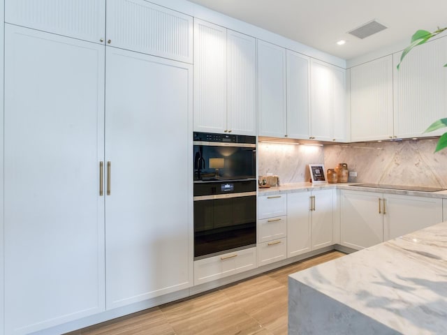 kitchen with visible vents, decorative backsplash, light stone counters, black appliances, and white cabinetry