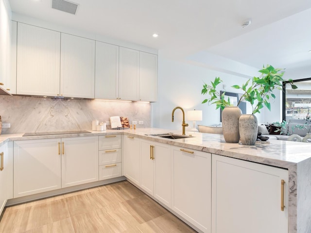 kitchen featuring black electric stovetop, tasteful backsplash, visible vents, white cabinetry, and a sink