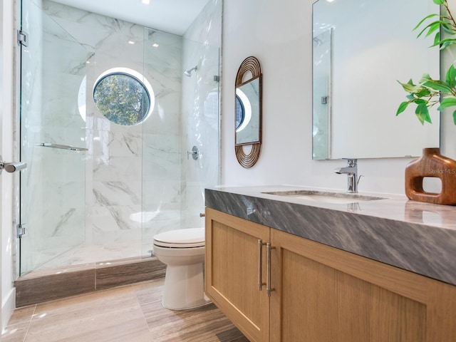 full bathroom with vanity, a marble finish shower, and toilet