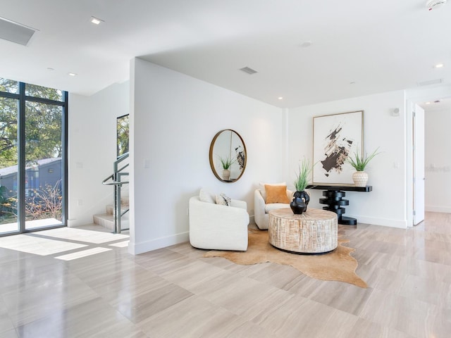 sitting room featuring expansive windows, stairs, baseboards, and recessed lighting