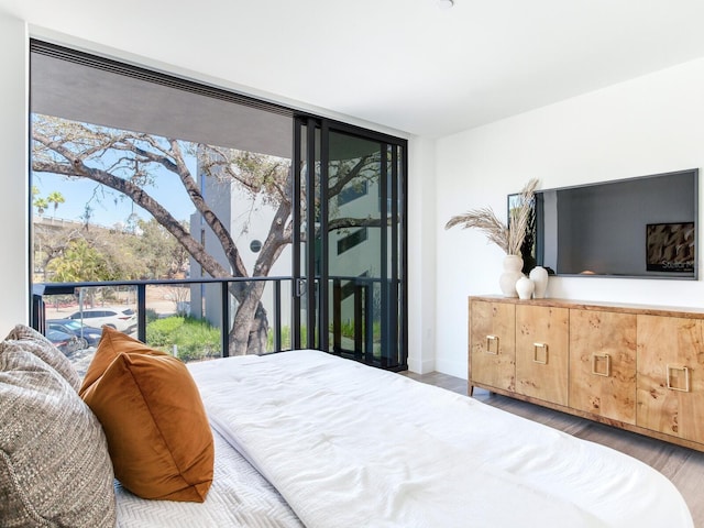 bedroom with expansive windows, multiple windows, and wood finished floors