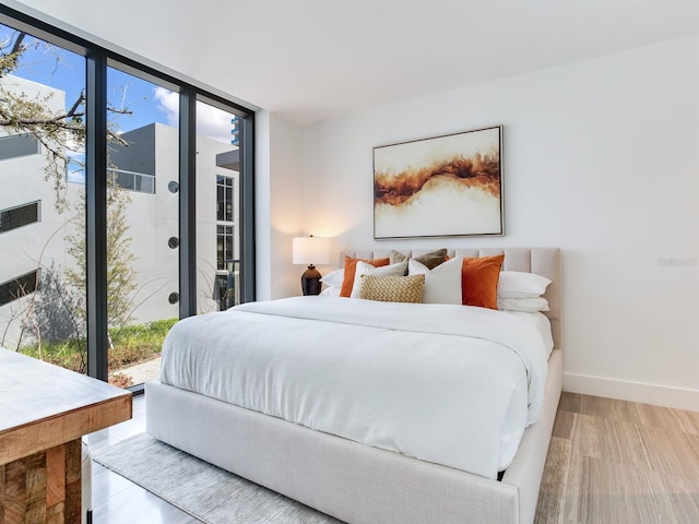 bedroom with wood finished floors, baseboards, access to outside, french doors, and expansive windows