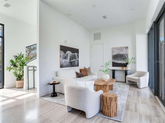 living area with baseboards, a high ceiling, and visible vents