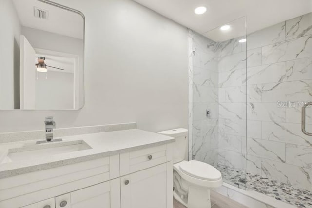 bathroom featuring marble finish floor, a marble finish shower, visible vents, toilet, and vanity