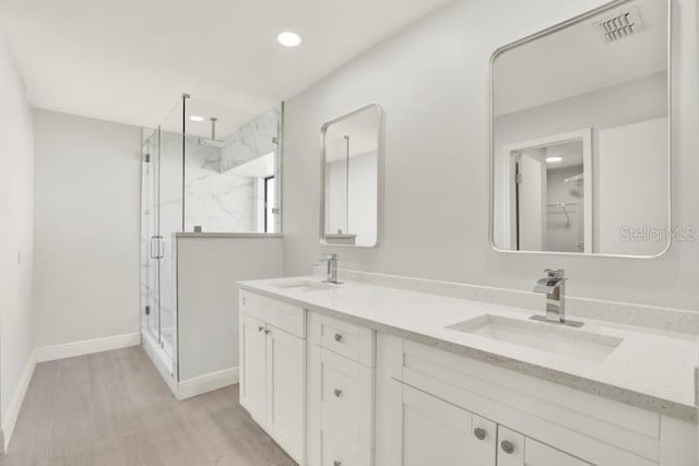 full bathroom with double vanity, a marble finish shower, visible vents, and a sink