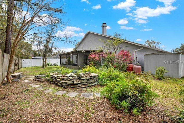 back of property with an outbuilding, a sunroom, and a fenced backyard