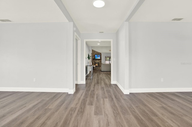 hall featuring visible vents, baseboards, and wood finished floors