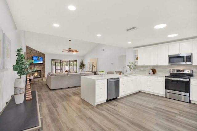 kitchen featuring a sink, visible vents, white cabinetry, open floor plan, and appliances with stainless steel finishes