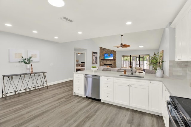 kitchen with a stone fireplace, a sink, visible vents, light wood-style floors, and appliances with stainless steel finishes