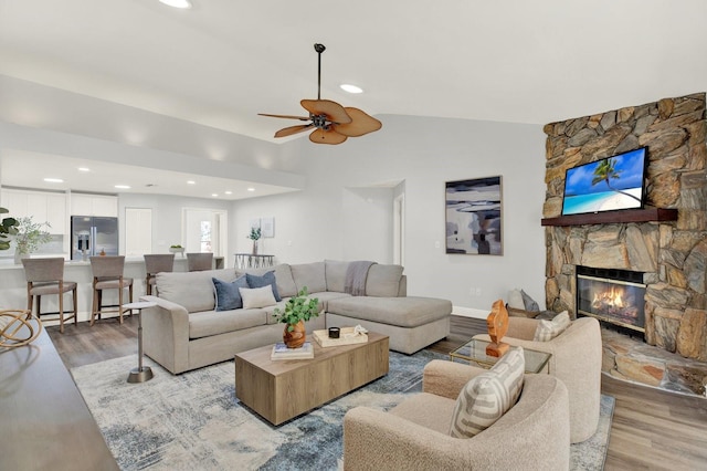 living room featuring a fireplace, vaulted ceiling, and wood finished floors