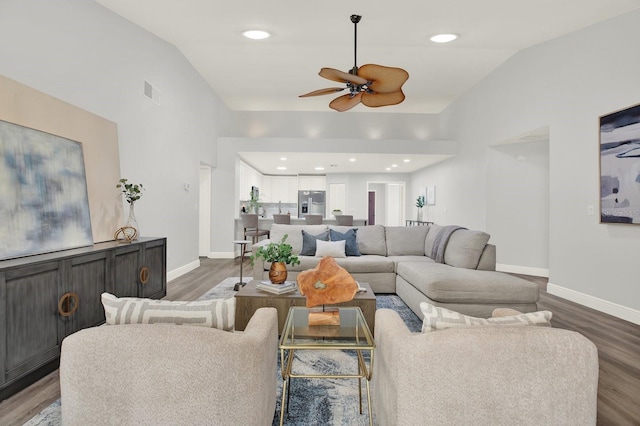 living area with vaulted ceiling, baseboards, and wood finished floors