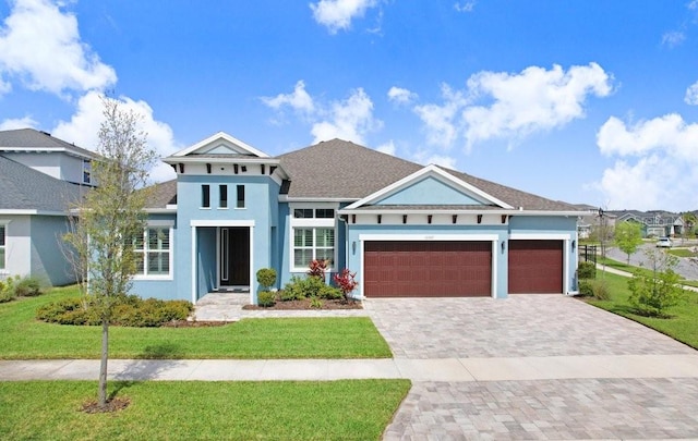 view of front facade with an attached garage, a front lawn, decorative driveway, and stucco siding