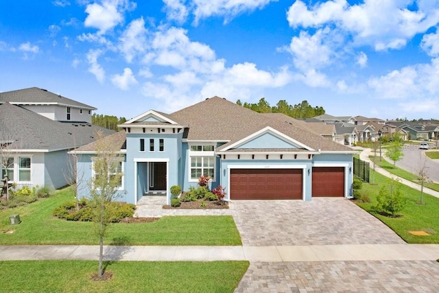 view of front of home with a garage, decorative driveway, a residential view, stucco siding, and a front yard