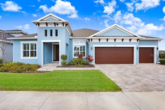 view of front of property with a garage, decorative driveway, a front yard, and stucco siding