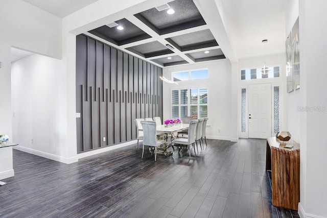 dining area with baseboards, coffered ceiling, a towering ceiling, wood finished floors, and beamed ceiling