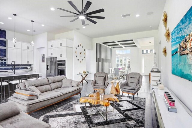 living area with a ceiling fan, recessed lighting, beam ceiling, and visible vents