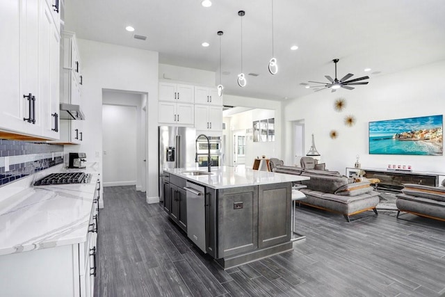 kitchen featuring stainless steel appliances, white cabinetry, open floor plan, and backsplash