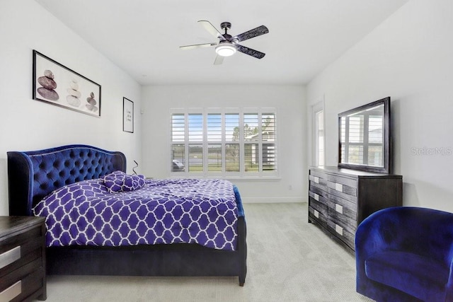 bedroom featuring light carpet, a ceiling fan, and baseboards