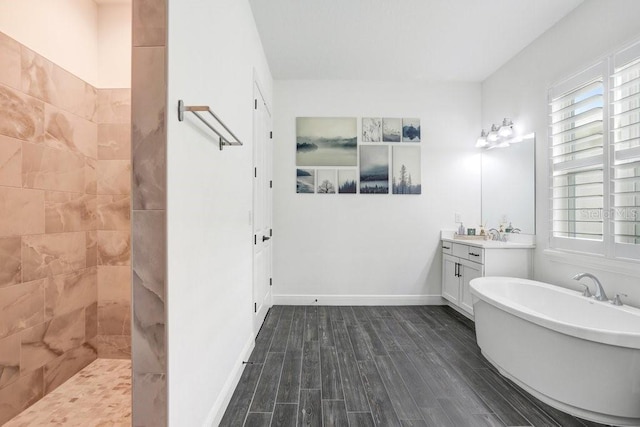 bathroom with a soaking tub, wood finished floors, vanity, a walk in shower, and baseboards