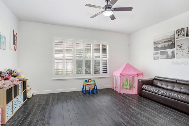 playroom with a ceiling fan, baseboards, and wood finished floors