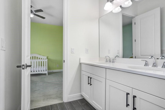 bathroom featuring double vanity, a sink, a ceiling fan, and baseboards