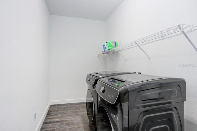 washroom with laundry area, baseboards, wood finished floors, and washing machine and clothes dryer