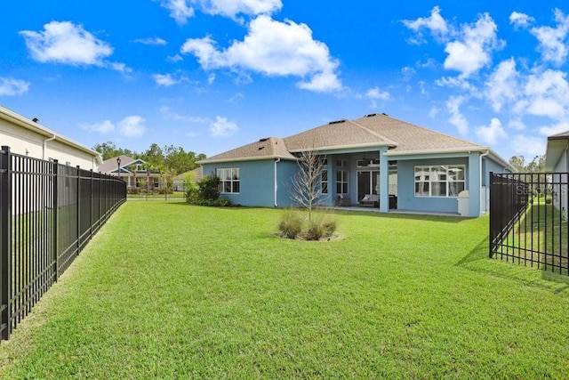 back of property with a fenced backyard, a lawn, and stucco siding