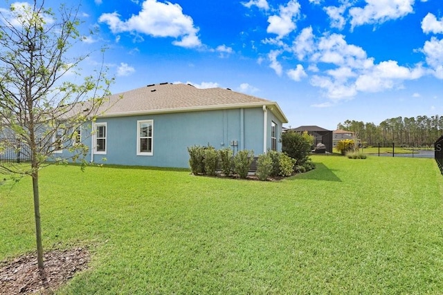 exterior space featuring a lawn, fence, and stucco siding