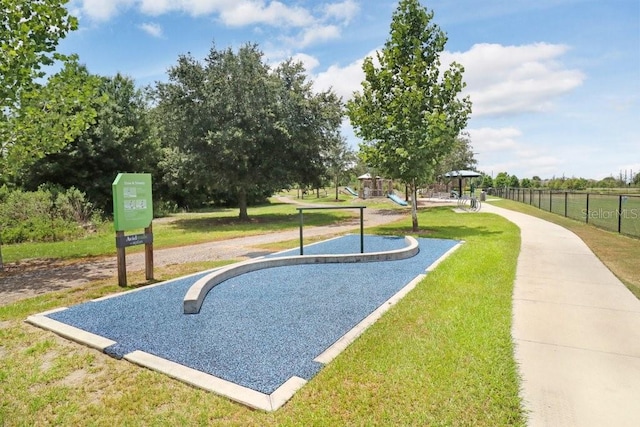 view of property's community with playground community, a yard, and fence