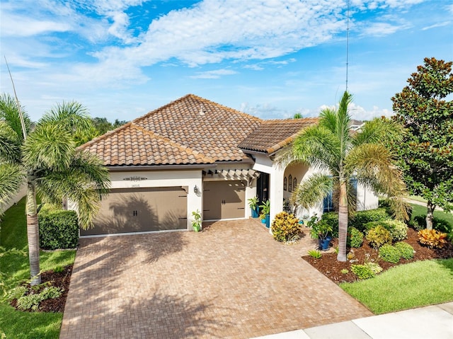 mediterranean / spanish-style house featuring a tiled roof, decorative driveway, an attached garage, and stucco siding