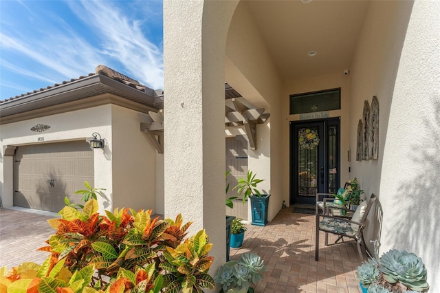 view of exterior entry featuring a garage and stucco siding