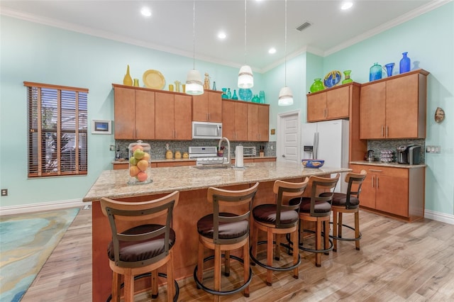 kitchen with light wood finished floors, white appliances, visible vents, and crown molding