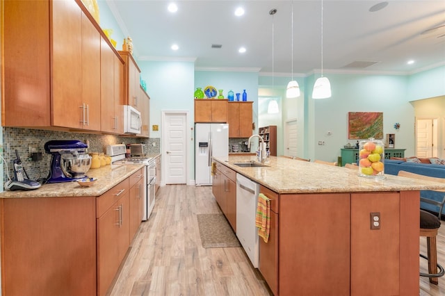 kitchen featuring a breakfast bar area, white appliances, a sink, light wood-style floors, and decorative backsplash