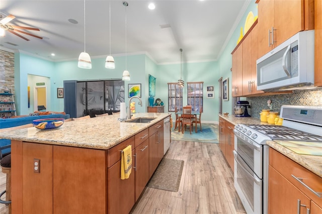 kitchen with white microwave, range with two ovens, a sink, a kitchen bar, and a center island with sink