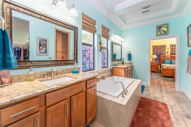 ensuite bathroom featuring a garden tub, crown molding, a sink, and wood finished floors