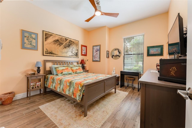 bedroom with light wood-type flooring, baseboards, and a ceiling fan