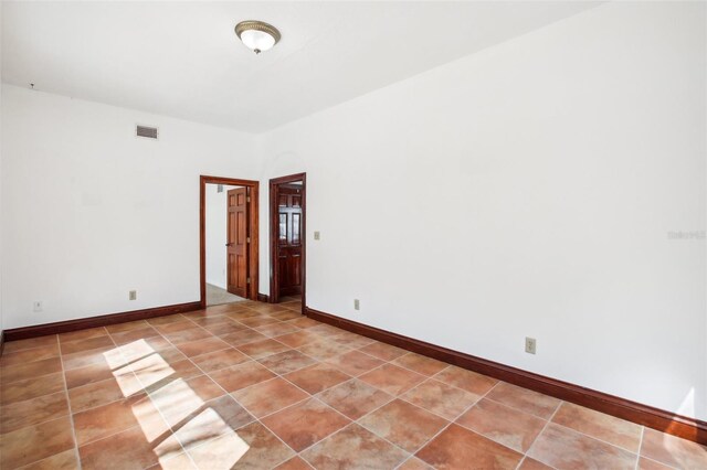 spare room with arched walkways, visible vents, baseboards, and light tile patterned floors