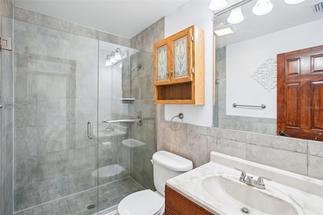 full bath with visible vents, toilet, a stall shower, and tile walls