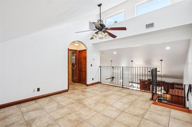 unfurnished room with visible vents, high vaulted ceiling, arched walkways, baseboards, and ceiling fan