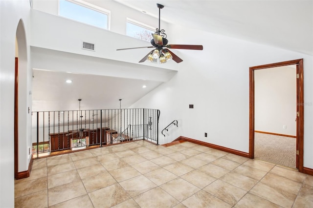 spare room with light tile patterned floors, a ceiling fan, visible vents, baseboards, and arched walkways