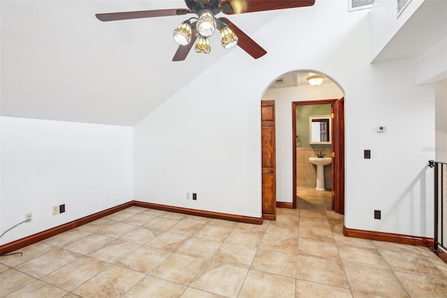 bonus room featuring baseboards, light tile patterned flooring, arched walkways, a sink, and vaulted ceiling