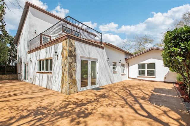 rear view of house featuring french doors, a patio, a balcony, and stucco siding