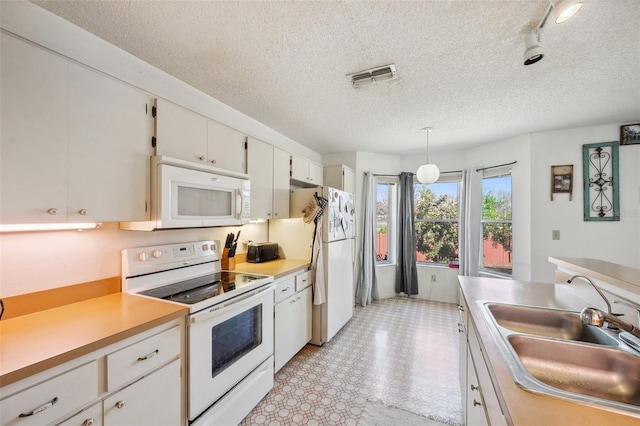 kitchen featuring light floors, light countertops, visible vents, a sink, and white appliances