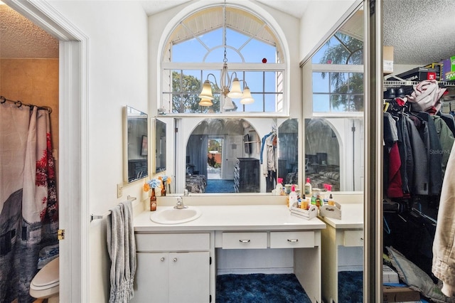 full bath with a textured ceiling, a spacious closet, vanity, and an inviting chandelier